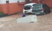 Homem usa geladeira como 'barco' para navegar em avenida alagada após temporal em Manaus